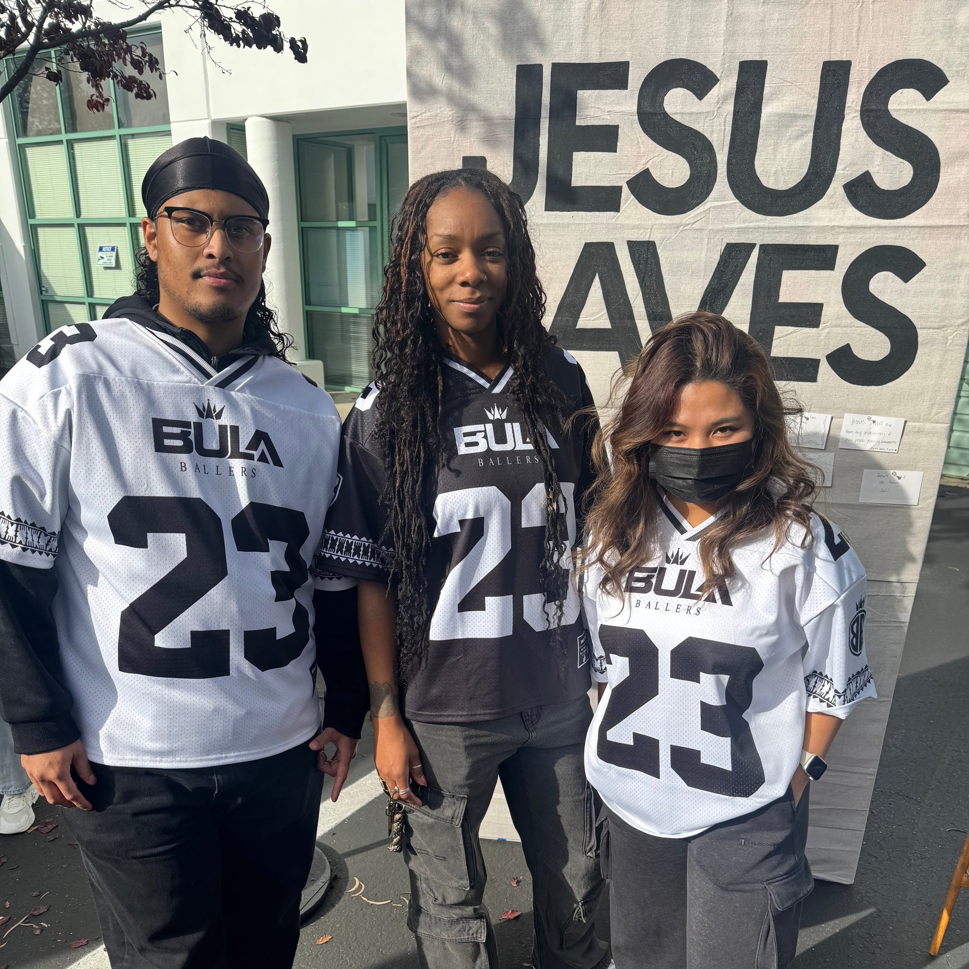 Three people wearing matching jerseys with the number 23 in an urban setting.
